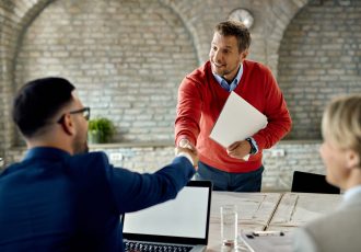 Happy male candidate shaking hands with members of human resource team on a job interview in the office.